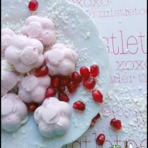 Keto fat bombs with pomegranate seeds and coconut on a white plate