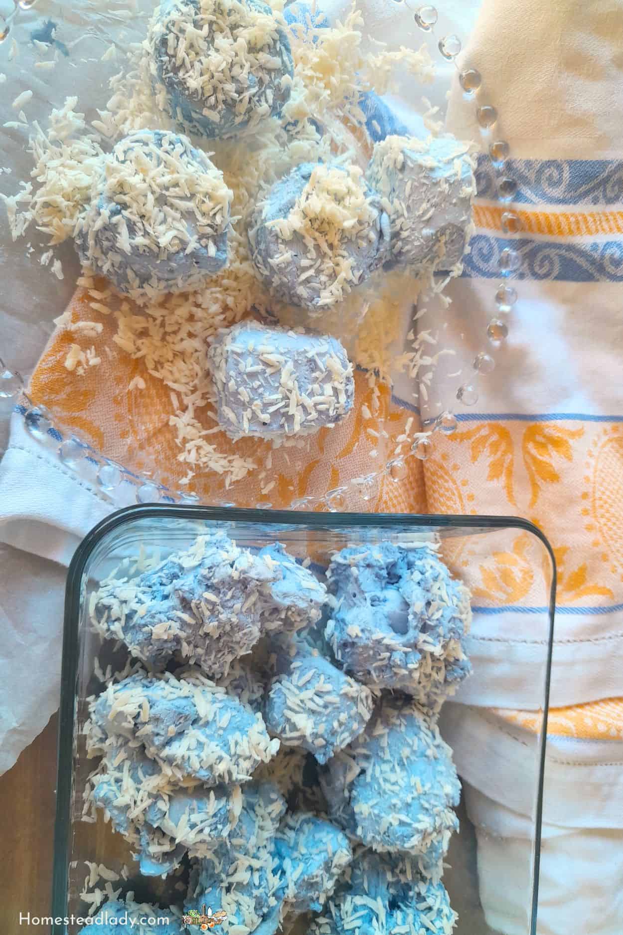 snowball marshmallows with blue plant dye rolled in coconut sitting on a plate