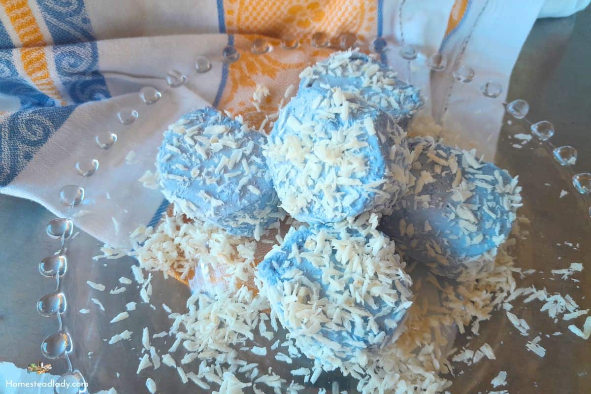 snowball marshmallows with blue plant dye rolled in coconut sitting on a plate